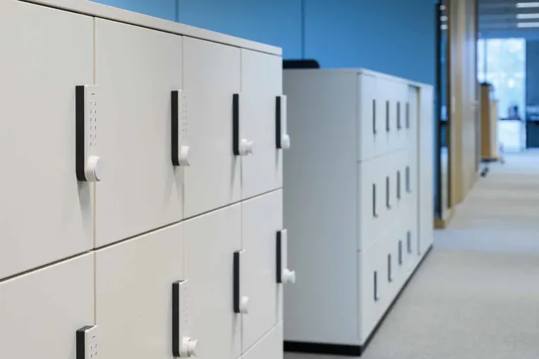 Serrures intelligentes RFID pour casiers Armoires de rangement blanches dans un bureau moderne avec des murs bleus.